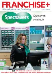 Specsavers-medewerker bij de kassa met producten op de achtergrond in een optiekwinkel, onder een groot Specsavers-logo.