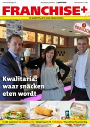 Drie mensen poseren in een snackbar met Kwalitaria-borden zichtbaar op de achtergrond.