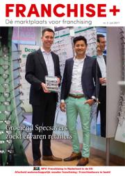 Twee mannen in pak poseren voor een Specsavers-winkel met een display-update over franchising.