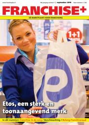 Vrouw in blauwe uniformwinkelkleding houdt Etos-tas vast met daarop promotie van 1+1 gratis binnen een winkelomgeving.