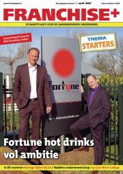 Twee mannen in pakken poseren bij een Fortune Hot Drinks-bord op de cover van Franchise+ nummer 2, april 2007.
