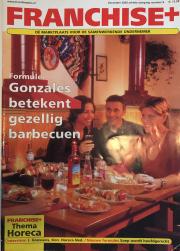 Groep mensen geniet van een gezellige barbecue in een restaurantsetting met eten en drankjes op tafel.