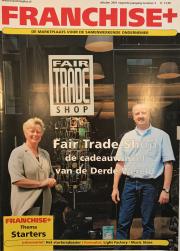 Twee mensen staan voor een Fair Trade Shop met tijdschriftenrek, omslag van Franchise+ tijdschrift oktober 2001.