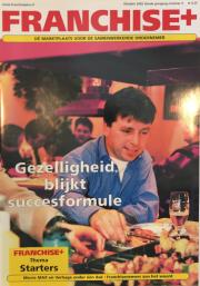 Man in blauw overhemd aan een tafel met eten en drank, tekst Gezelligheid blijkt succesformule op de voorgrond.