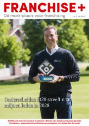 Man in fit20-kleding houdt een trofee vast in een groene buitenomgeving, op de cover van Franchise+ magazine.