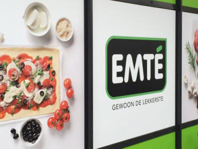 EMTÉ-reclamebord met afbeeldingen van een pizza en diverse ingrediënten aan een buitenmuur.