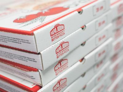 Stapels Papa John's pizzadozen liggen klaar, versierd met het kenmerkende logo en slogan.