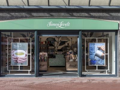 Simon Lévelt winkel met posters over thee en koffie aan weerszijden van de ingang, interieur met producten zichtbaar.