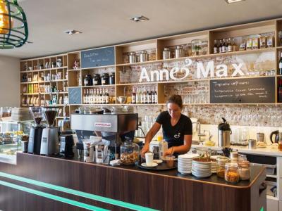Barista bereidt koffie achter de houten toonbank van de nieuwe Anne&Max-vestiging in Breda, omgeven door producten.