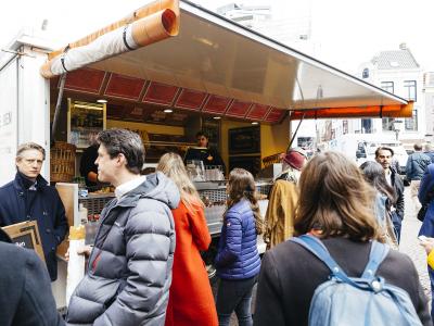 Mensen staan in de rij voor een Broodje Ben foodtruck op een plein in Houten.