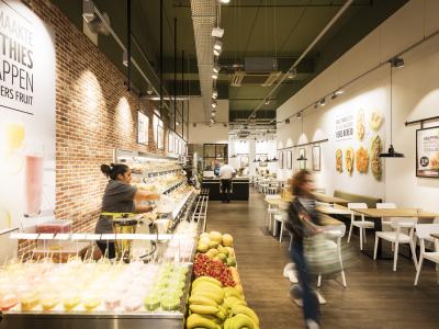 Interieur van een Backwerk-filiaal in Hilversum met vers fruit, smoothies en klant aan de toonbank.