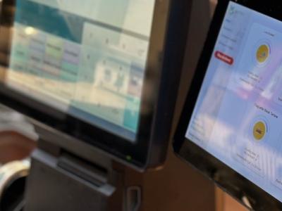 Twee digitale schermen op een toonbank met kassasoftware en voorraadbeheer.