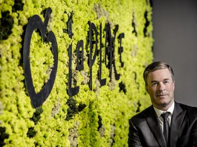 Meneer in pak poseert voor een groene muur met het logo van La Place.