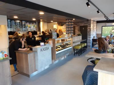 Interieur van Big Bread Kitchen met personeel achter de kassa en klanten in de eetruimte.