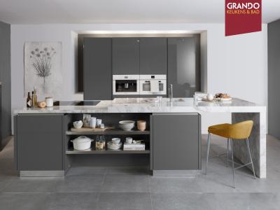 Moderne keukenopstelling met grijze kasten, marmeren werkblad en ingebouwde apparaten in de nieuwe Grando vestiging.