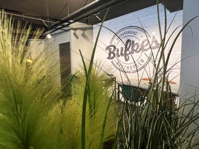 Interieur van de nieuwste Bufkes-vestiging in Heythuysen met groen decor en een muur met het Bufkes-logo.