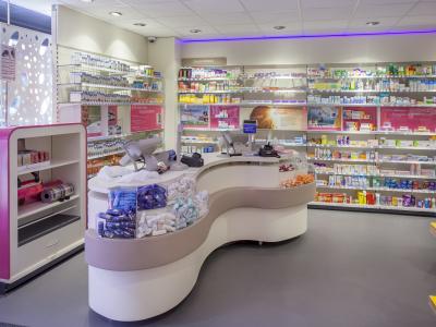 Interieur van een moderne drogisterij met een balie en schappen vol verzorgingsproducten en medicijnen.