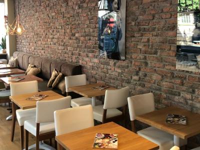 Interieur van een modern Barista Cafe met houten tafels, witte stoelen en bakstenen muur.