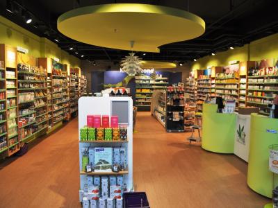 Interieur van een gezondheidswinkel met kleurrijke producten, schappen en een kassamedewerker op de voorgrond.