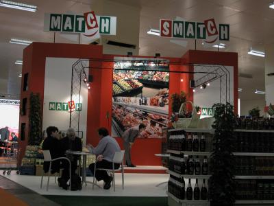 Stand van Match en Smatch op de Belgische Franchise Beurs, met mensen die aan een tafel in gesprek zijn.