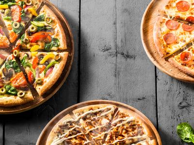 Drie verschillende pizza's op houten borden, gepresenteerd op een donkere houten tafel, met verse ingrediënten.