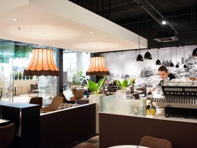 Interieur van Doppio Espresso Wageningen met sfeervolle verlichting, planten en een barista achter de espressobar.