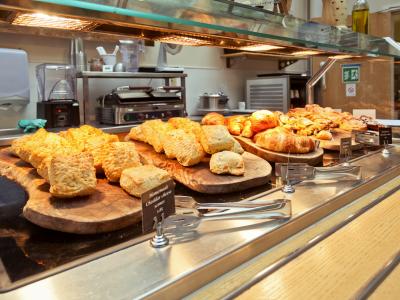 Uitgestald assortiment van gebak en broodjes op houten planken in een foodserviceomgeving.