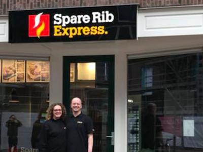 Voorgevel van een Spare Rib Express met twee personen in bedrijfskleding voor de ingang.