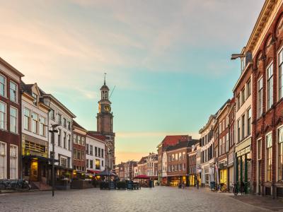 Straat met historische gebouwen en een klokkentoren bij zonsondergang in een rustige stadsomgeving.