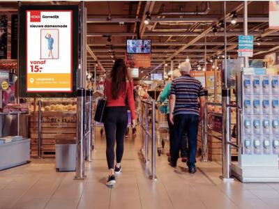 Winkelgang in Albert Heijn met klanten en HEMA-promotiebord voor damesmode bij ingang.