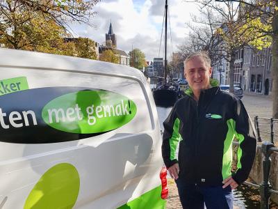 Nieuwe franchisenemer poseert naast een Eten met gemak bezorgbusje aan een gracht in Rotterdam.