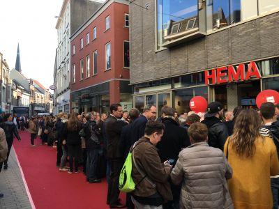 Mensen staan in de rij bij een HEMA-filiaal aan een winkelstraat met rode loper.