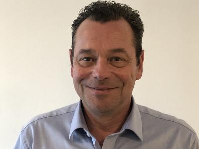 Man in blauw overhemd met Motorhome Depot-logo, tegen een neutrale achtergrond.