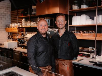 Twee mannen in schorten staan in de moderne keuken van Kwalitaria Délifrance in Arnhem.