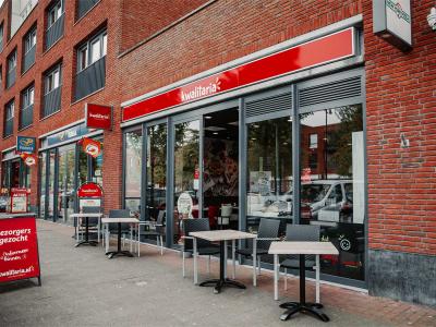Gevel van Kwalitaria Groeneweg met terras en bord waarop bezorgers worden gezocht.