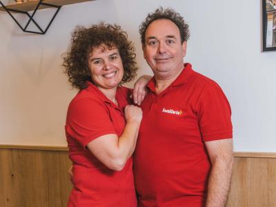 Twee medewerkers van Kwalitaria Zoetermeer in rode bedrijfskleding poseren lachend in de vernieuwde zaak.