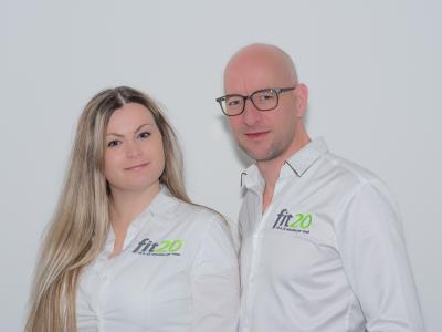 Twee personen in witte fit20-overhemden poseren voor de camera bij de nieuwe fit20 vestiging in Eindhoven.