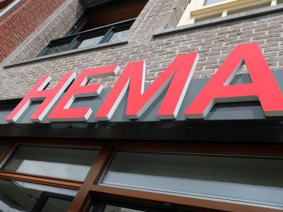 Gevel van een HEMA-winkel met prominent rood logo op grijze achtergrond.