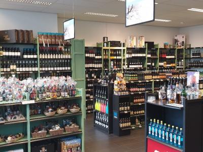 Interieur van een Mitra drankenspeciaalzaak met goed gevulde schappen vol flessen wijn en sterke dranken.