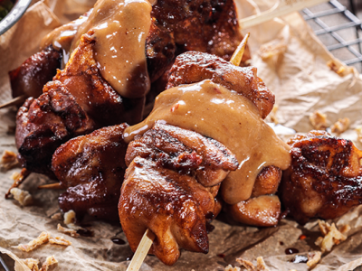 Saté met saus van Spare Rib Express gepresenteerd op bakpapier naast een frisse salade en coleslaw.