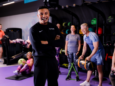 Groepsworkout in een sportschool onder leiding van een enthousiaste coach met blije deelnemers.
