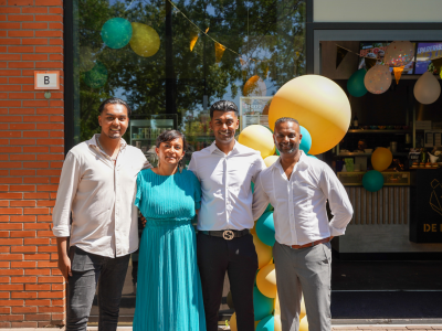 Vier personen staan voor het bezorgrestaurant De Beren Rijswijk, versierd met ballonnen en feestelijke decoraties.