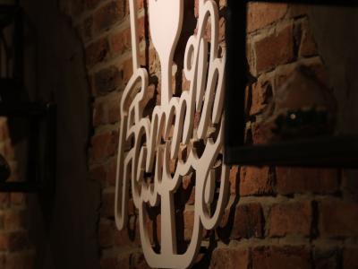 Wit Family-logo op een bakstenen muur met sfeerverlichting op de achtergrond.