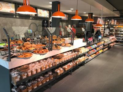 Interieur van een SPAR express-winkel met versgebakken broodjes en diverse producten op schappen.