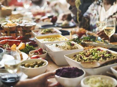 Een kleurrijke Indonesische buffetmaaltijd met diverse gerechten en mensen die genieten aan een rijk gedekte tafel.