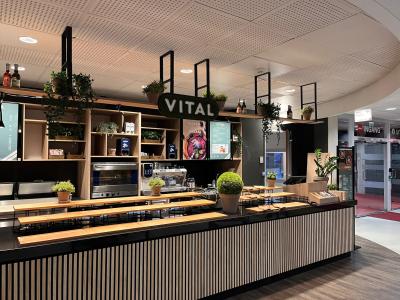 VITAL-cateringstation in een moderne ruimte met houten inrichting en groene planten.