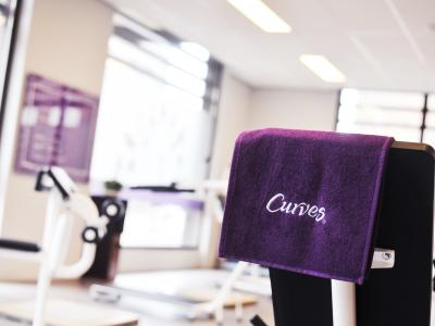 Binnenruimte van een Curves-fitnessstudio met paarse handdoek over de machine.