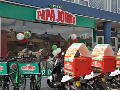 Gevel van de nieuwe Papa John’s in Eindhoven met bezorgscooters en fietsen voor de opening.