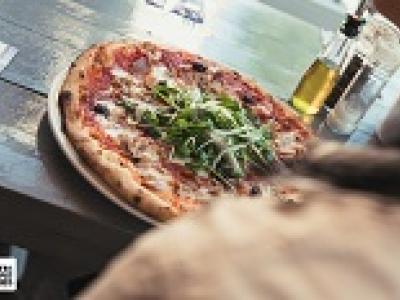 Pizza met rucola en olijfolie op tafel bij De Pizzabakkers in Hilversum.