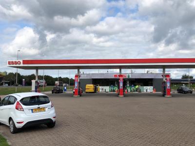 Esso tankstation met een Spar express winkel, diverse geparkeerde auto's en pompen zichtbaar.
